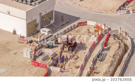 Group of worker and red excavator diging water drainage at construction site aerial timelapse. Group of worker and red excavator diging water drainage at construction site aerial timelapse. 103762608