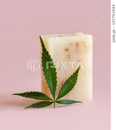 Craft soap bar near green cannabis leaves on pink close up. Cosmetic Mockup 103762694
