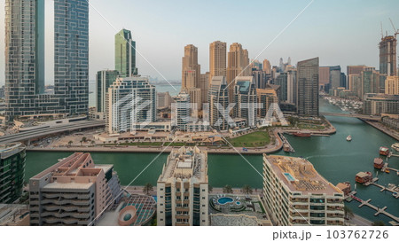 Panorama showing Dubai Marina with several boat and yachts parked in harbor and skyscrapers around canal aerial timelapse. Panorama showing Dubai Marina with several boat and yachts parked in harbor and skyscrapers around canal aerial timelapse. 103762726