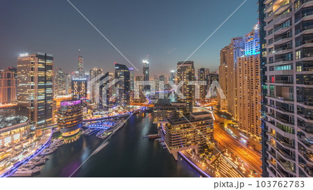 Aerial view to Dubai marina skyscrapers around canal with floating boats day to night timelapse 103762783