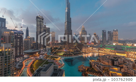 Skyscrapers rising above Dubai downtown day to night timelapse surrounded by modern buildings aerial top view Skyscrapers rising above Dubai downtown day to night timelapse surrounded by modern buildings aerial top view 103762980