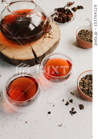 Different types of tea. Black, green and hibiscus sorts on a white table with teapot and glasses. 103764129