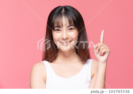 Young Beautiful Asian woman smile with clean and fresh skin Happiness and cheerful with positive emotional pointing up,isolated on pink background,Beauty Cosmetics and spa Treatment Concept 103765536