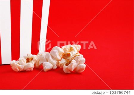 Glass with popcorn on a red background Glass with popcorn on a red background 103766744