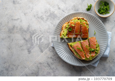 Toast with salmon, guacamole avocado and herbs. Healthy food. Top view, copy space. Toast with salmon, guacamole avocado and herbs. Healthy food. Top view, copy space. 103770709