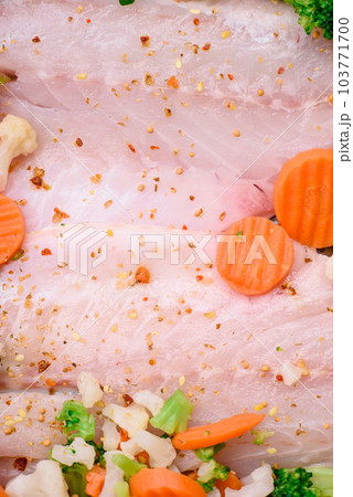 Raw sea bass fish fillet with salt, spices and vegetables in a baking dish Raw sea bass fish fillet with salt, spices and vegetables in a baking dish 103771700