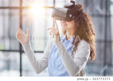 positive woman wearing virtual reality goggles headsetConnection, technology, new generation, progress concept. positive woman wearing virtual reality goggles headsetConnection, technology, new generation, progress concept. 103773373