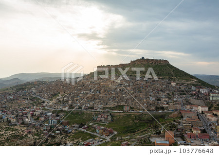 トルコ　丘から見えるマルディンの旧市街の街並みと山頂に立つマルディン城と夕焼け空 103776648