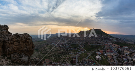 トルコ　丘から見えるマルディンの旧市街の街並みと山頂に立つマルディン城と夕焼け空 103776661