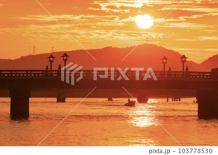 宍道湖の朝日に照らされて出漁するシジミ漁船 103778530