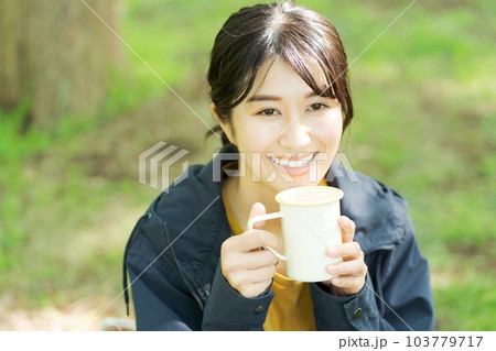 屋外でコーヒーを飲む女性の写真 103779717