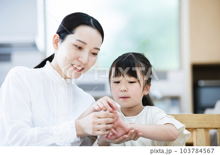 娘に絆創膏を貼る母親 103784567