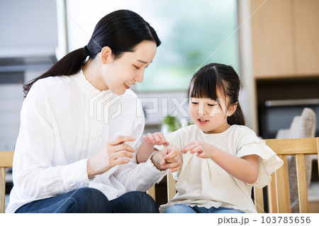 お母さんに絆創膏を貼ってあげる女の子 103785656