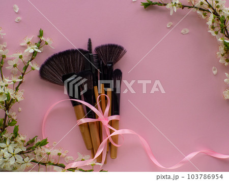 Bouquet of cosmetic brushes tied with a ribbon with a bow on pink background Bouquet of cosmetic brushes tied with a ribbon with a bow on pink background 103786954