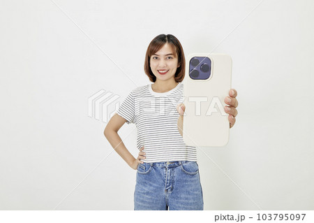 Young Asian female in t-shirt and blue jeans showing smartphone 103795097