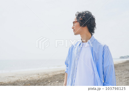 海岸を歩く青いストライプシャツを着た男性 海岸を歩く青いストライプシャツを着た男性 103798125