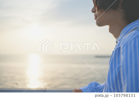 沈みゆく夕日を橋の上から眺める男性 沈みゆく夕日を橋の上から眺める男性 103798131