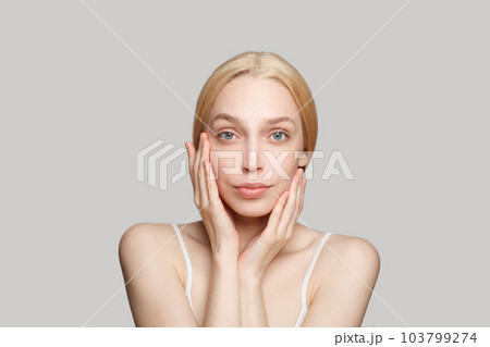 Beautiful blonde woman with perfect clear shiny skin looking at camera.  103799274