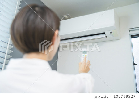 エアコンを操作する若い女性　ライフスタイルイメージ	 103799527