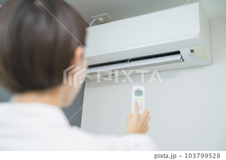 エアコンを操作する若い女性　ライフスタイルイメージ	 103799528