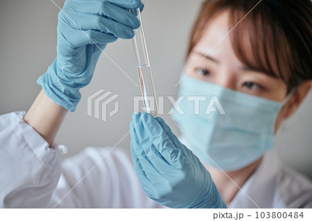 実験をする白衣の若い女性 103800484