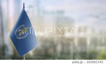 A small World Health Organization WHO flag on an abstract blurry background 103801342