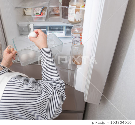 【冷蔵室からたまごを取り出す主婦】 103804010