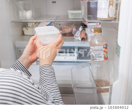 【冷蔵室からタッパを取り出す主婦】 103804012