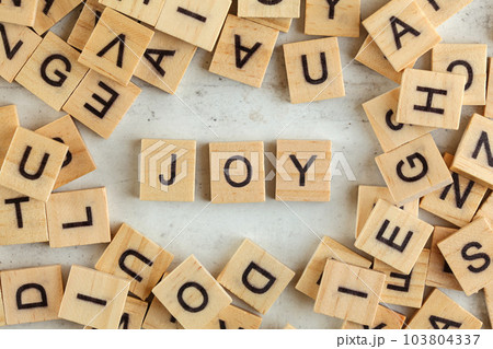 Top down view, pile of square wooden blocks with word JOY on white board. Top down view, pile of square wooden blocks with word JOY on white board. 103804337