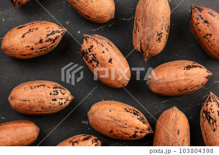 Overhead shot, whole pecan nuts in shell on black board. 103804398