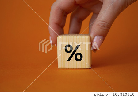 Percentage sign symbol. Percentage sign on wooden cubes. Businessman hand. Beautiful orange background. Business and Percentage sign concept. Copy space. 103810910