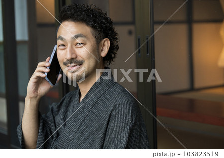 浴衣でスマホで電話や連絡をする髭の中年男性のアップ 103823519