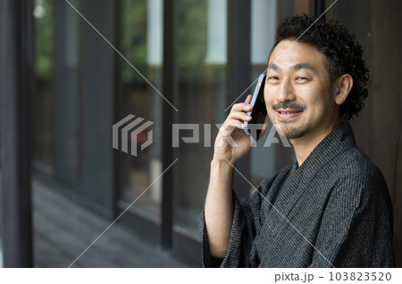 浴衣でスマホで電話や連絡をする髭の中年男性のアップ 103823520