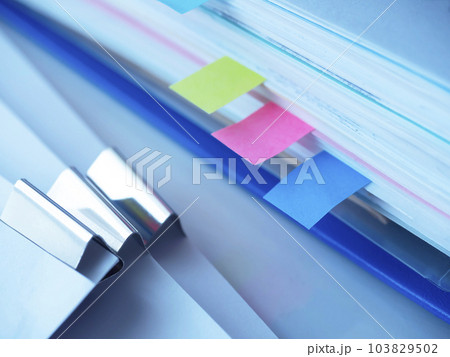 テーブルに置かれた青いファイルと書類 103829502