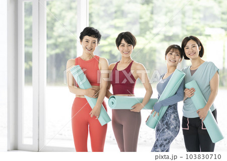 ヨガマットを持ったカメラ目線で笑顔の4人の女性 103830710