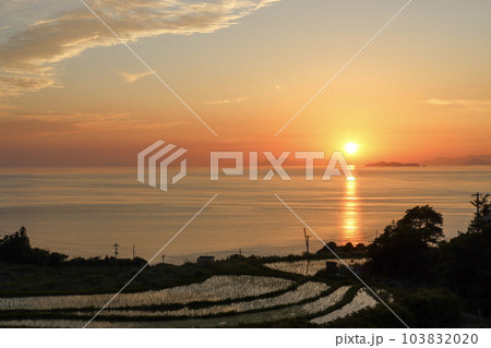 オレンジ色の夕焼け空に沈む夕日と棚田 オレンジ色の夕焼け空に沈む夕日と棚田 103832020