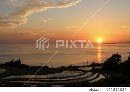 オレンジ色の夕焼け空に沈む夕日と棚田 103832022