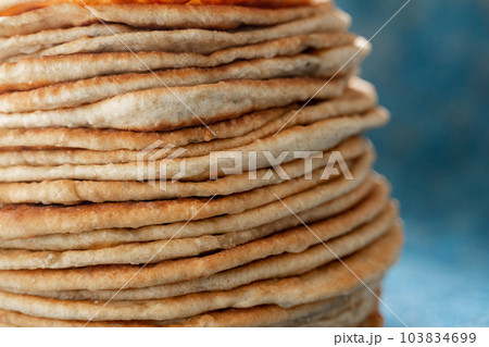 Flatbread lavash, chapati, naan, heap of tortilla on a blue background Homemade flatbread stacked. Flatbread lavash, chapati, naan, heap of tortilla on a blue background Homemade flatbread stacked. 103834699