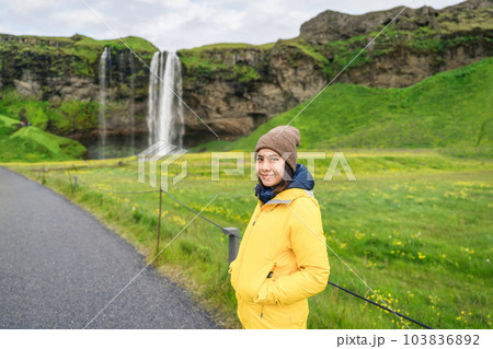 Asian tourist woman standing at front of Seljalandsfoss waterfall in summer Asian tourist woman standing at front of Seljalandsfoss waterfall in summer 103836892