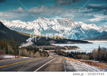 View of highway road into the rocky mountains and frozen lake in Icefields Parkway 103837430