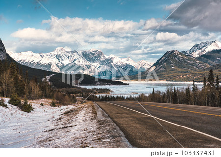 View of highway road into the rocky mountains and frozen lake in Icefields Parkway View of highway road into the rocky mountains and frozen lake in Icefields Parkway 103837431