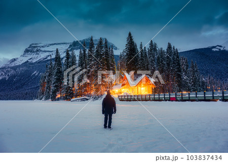Traveler man standing in snowfield with wooden lodge glowing and pine forest in rocky mountains at Yoho national park Traveler man standing in snowfield with wooden lodge glowing and pine forest in rocky mountains at Yoho national park 103837434