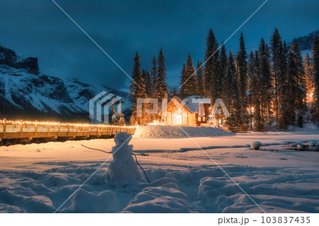 Snowy Emerald lake with wooden lodge glowing in pine forest and snowman in the night at Canada Snowy Emerald lake with wooden lodge glowing in pine forest and snowman in the night at Canada 103837435