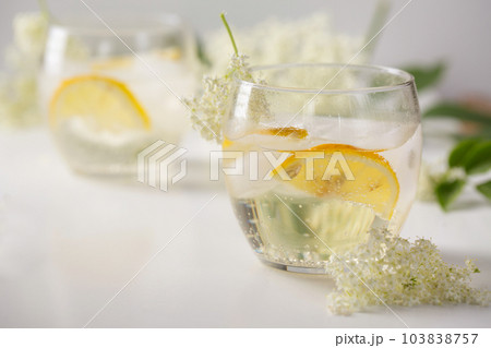 A cold drink made of elderflowers and lemon with ice on a light background 103838757