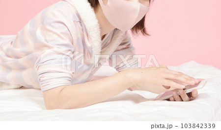 パジャマ姿でスマホを操作する女性 パジャマ姿でスマホを操作する女性 103842339