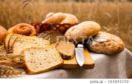 lot of different flavored bread, wheat, rye, on the table in the field outside lot of different flavored bread, wheat, rye, on the table in the field outside 103843159