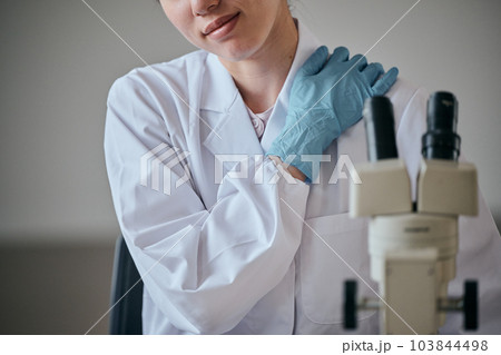 肩が凝り手で押さえる白衣の若い女性 103844498