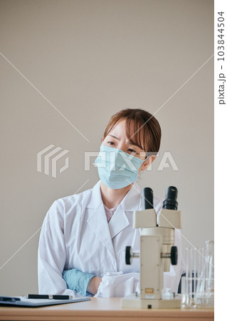 腕を組んで考え事をする白衣の若い女性 103844504