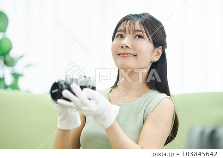 フリマアプリを使って不用品を販売する前に商品を確認する女性 フリマアプリを使って不用品を販売する前に商品を確認する女性 103845642