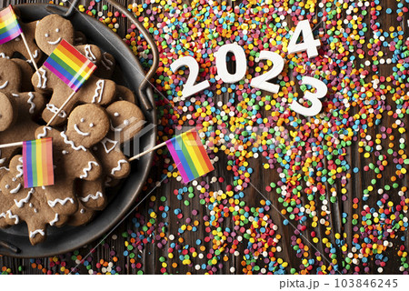 New year background of tray with gingerbread cookie men, rainbow flags and color sprinkles on wooden table New year background of tray with gingerbread cookie men, rainbow flags and color sprinkles on wooden table 103846245